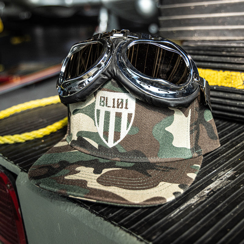 Camouflage snapback hat with white embroidered BL101 shield logo design on the front