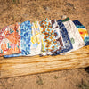 Eight patterned shorts on a wooden log with a natural outdoor background
