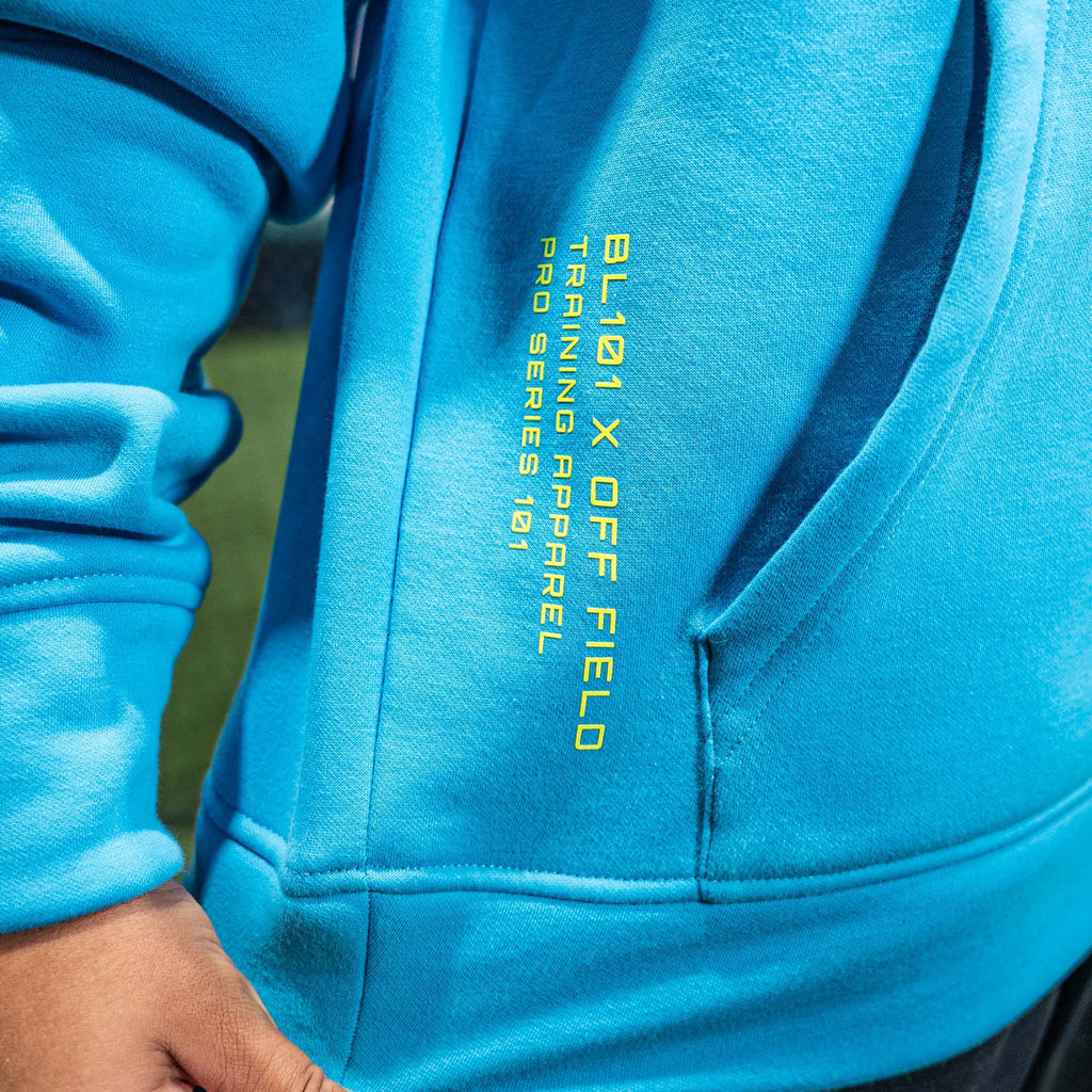Close-up of a blue hoodie with yellow 'BL101 X OFF FIELD' text on the side.