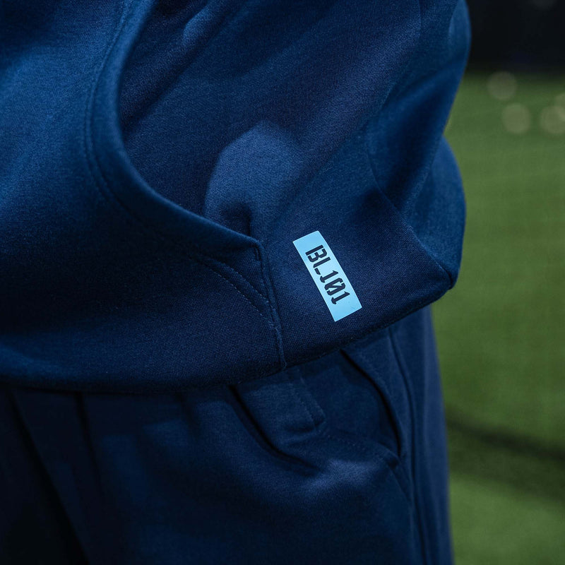 Navy blue hoodie with BL101  logo on a blurred green background