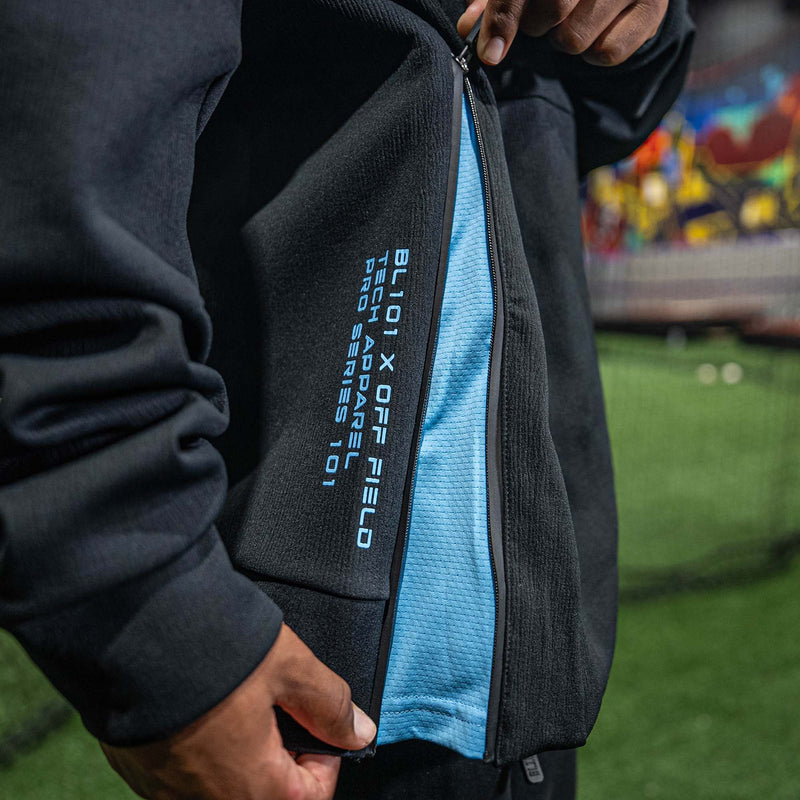 Person wearing black and blue hoodie with BL101 x OFF FIELD branding