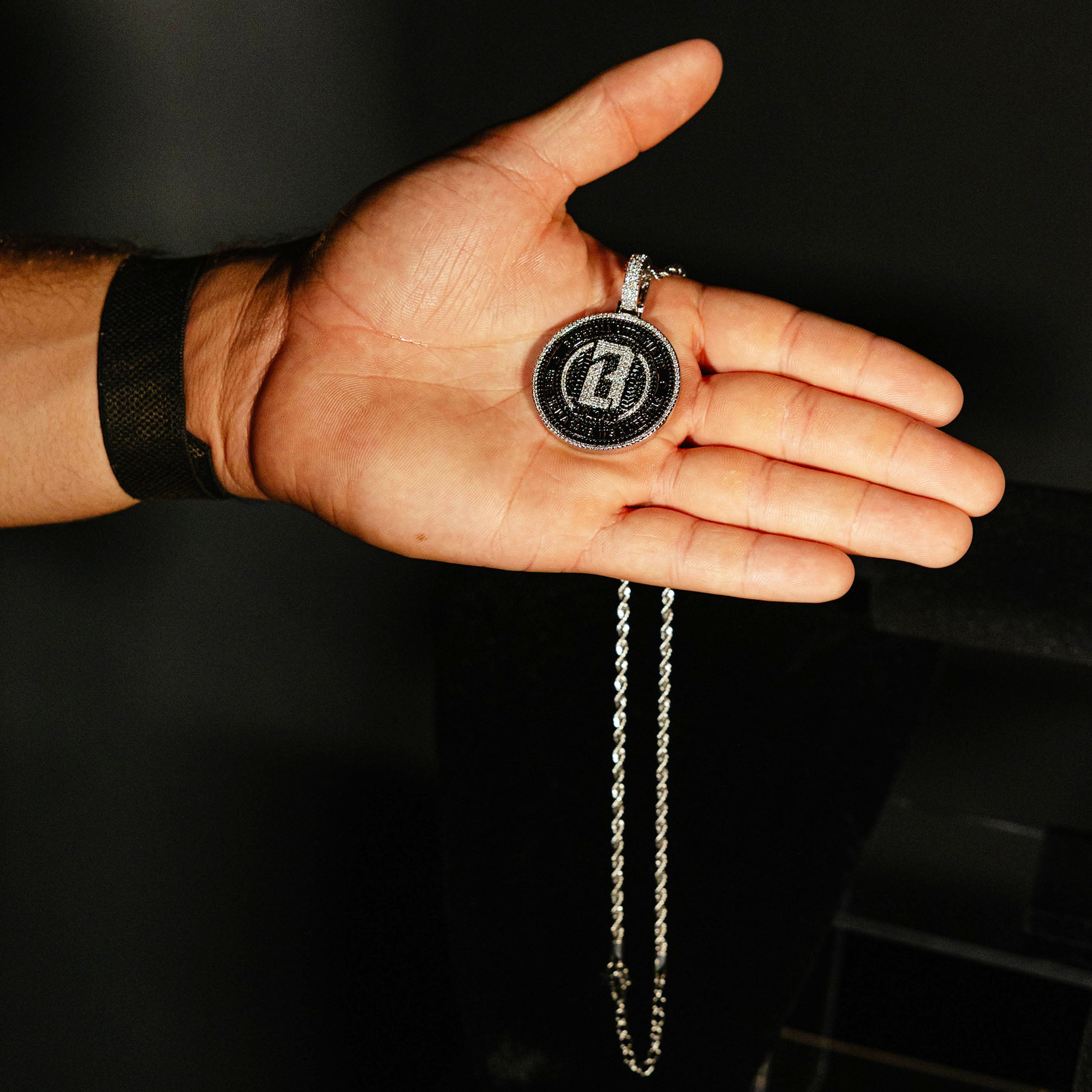 Model holding White Gold BL101 Medallion necklace against a black background