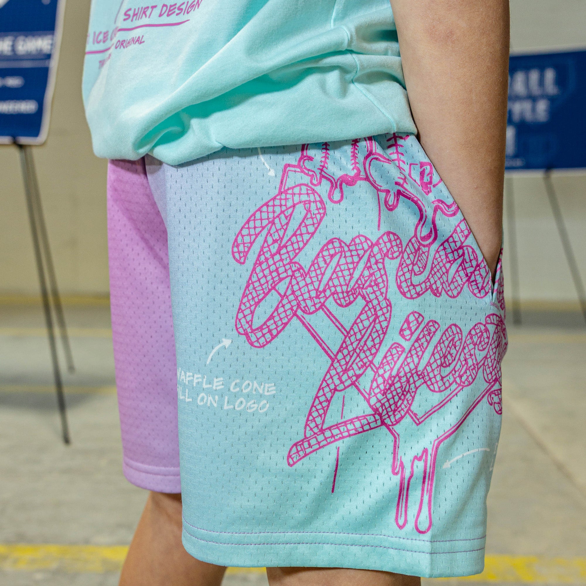 Person wearing light blue and pink shorts with pink graphic BL101 design and text.