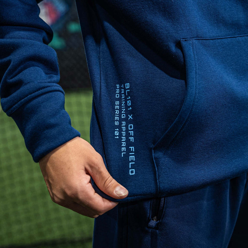 Person wearing a blue hoodie with BL101 X OFF FIELD text on the side, standing on a grassy field.