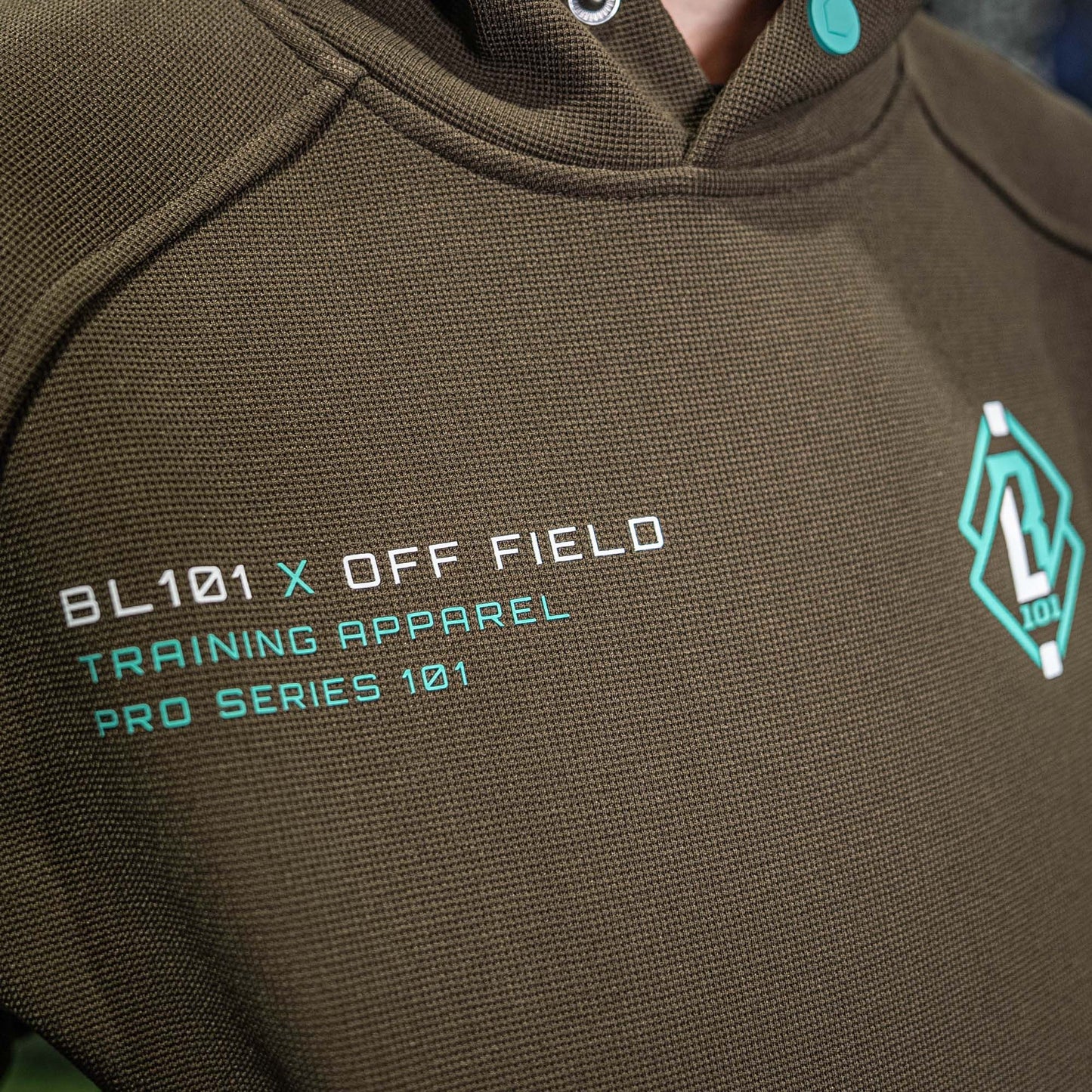 Brown hoodie with BL101 OFF FIELD text and logo on a blurred background