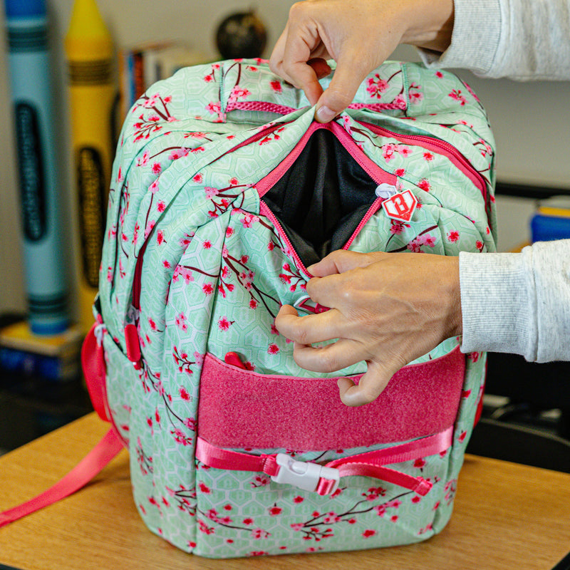 Green backpack with "Cherry Blossoms SZN 2" design — back view