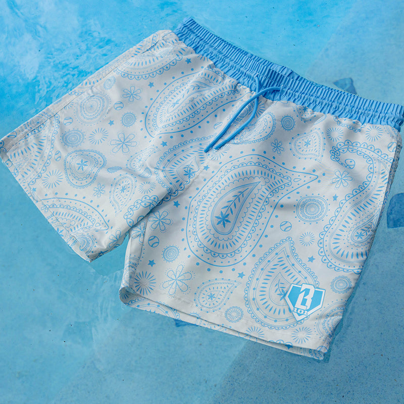 BL101 white and light blue baseball paisley swim shorts laid flat on a wet pool deck.
