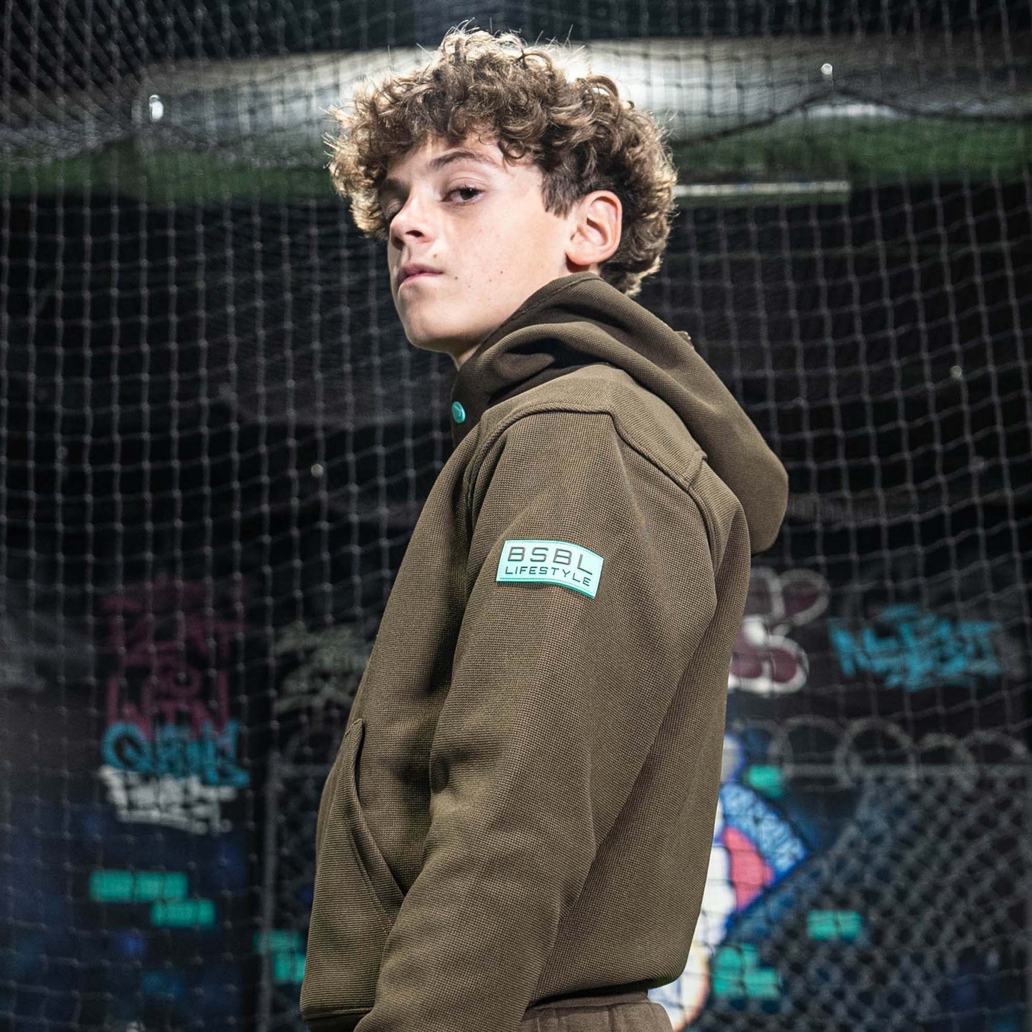 Person wearing a brown hoodie with a BL101 logo in front of a colorful, abstract background