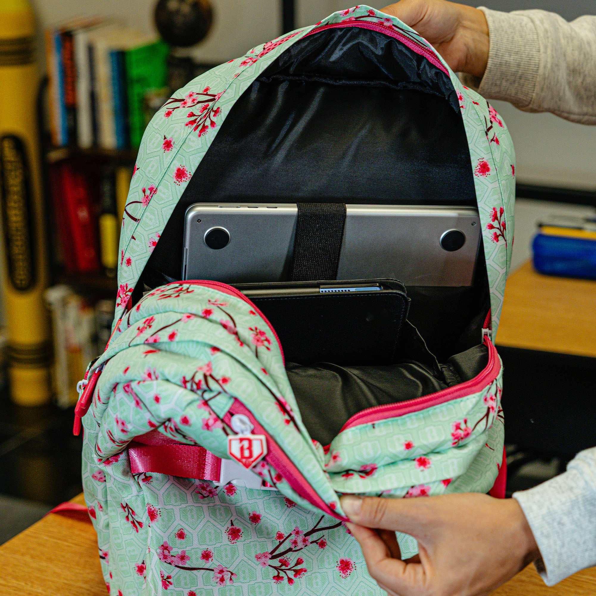 Green backpack with "Cherry Blossoms SZN 2" design — back view