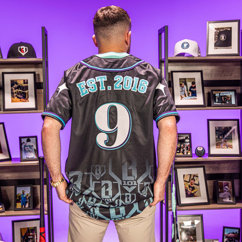 Person wearing a sports jersey with 'EST. 2016' and number '9' in a room with framed photos on shelves.