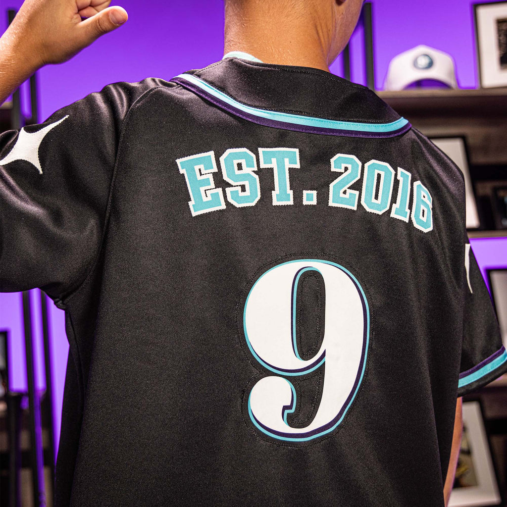 Close up of person wearing a black sports jersey with 'EST. 2016' and number '9' on a purple background