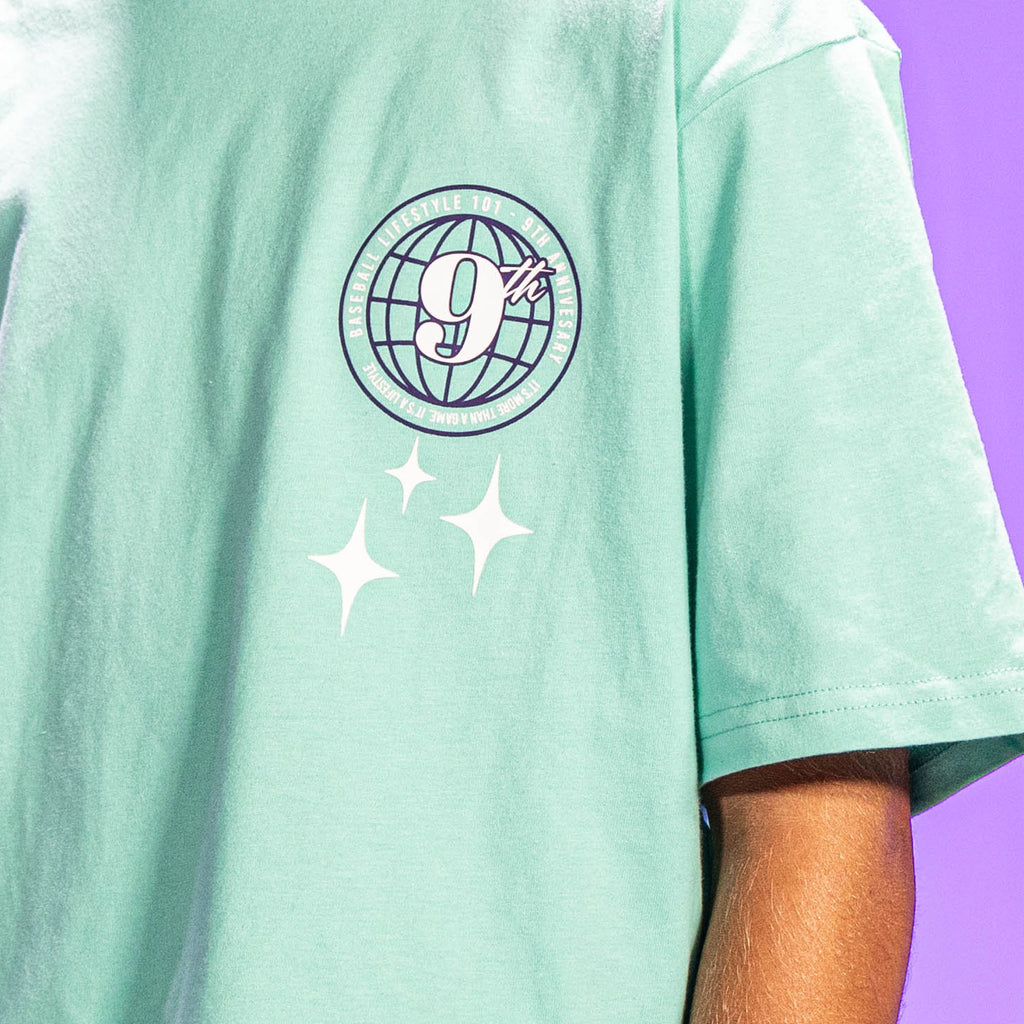 Mint green t-shirt with a 9th anniversary Baseball Lifestyle 101 logo and stars on the back against a purple background