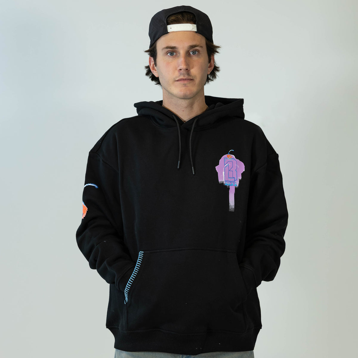 Adult model wearing black hoodie with "Fastball Scoops" design