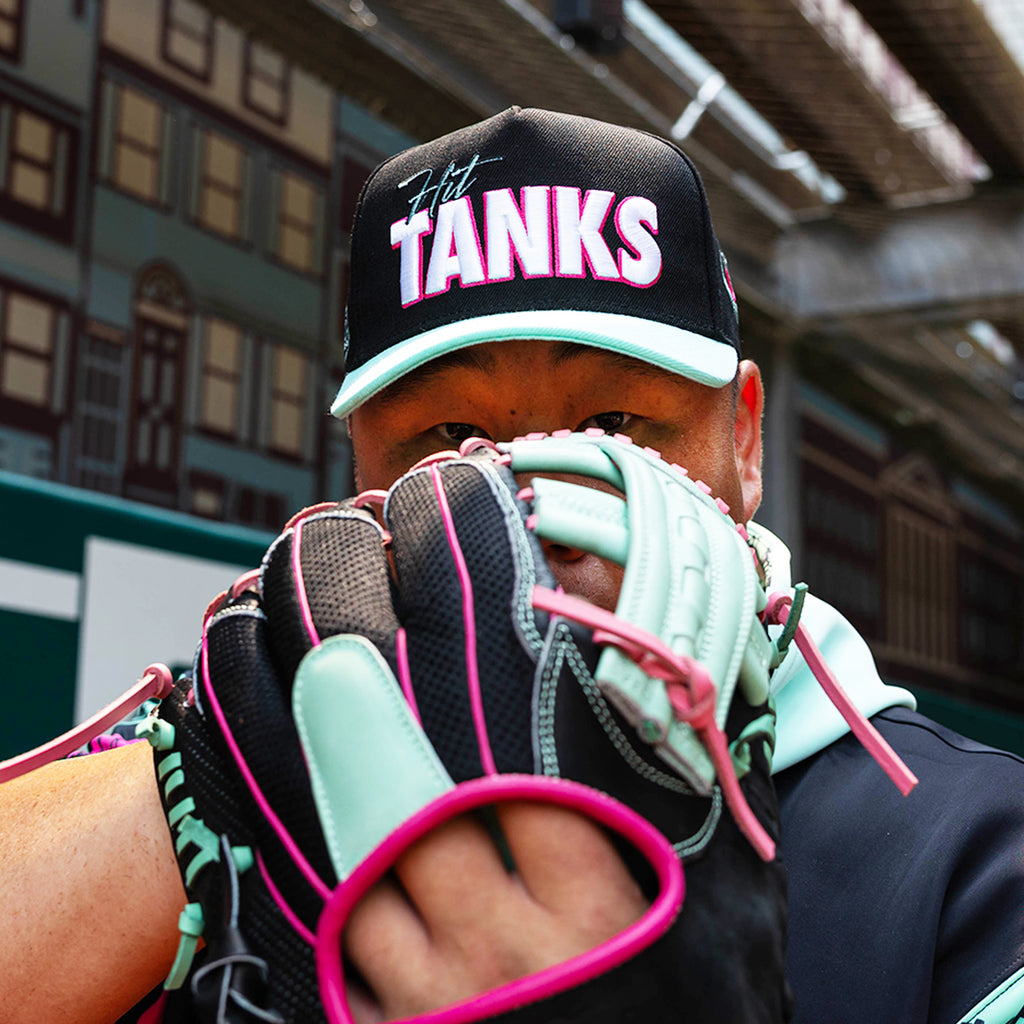 Adult model wearing black hat with "Hit Tanks" design