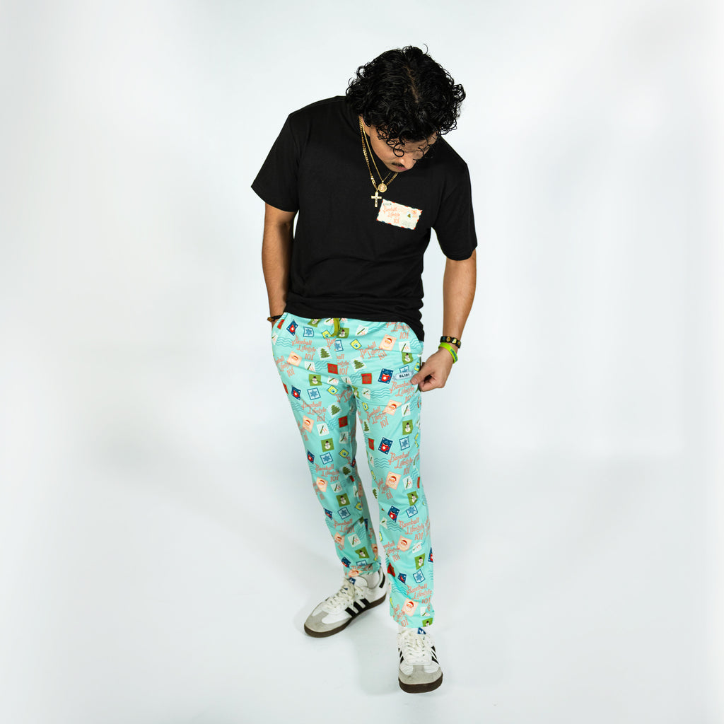 Adult model wearing teal pajama pants with "Holiday Stamps" design