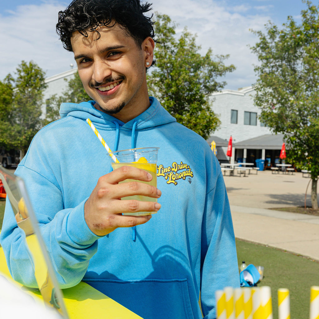 Adult model wearing blue hoodie with "Lemonade Cup" design