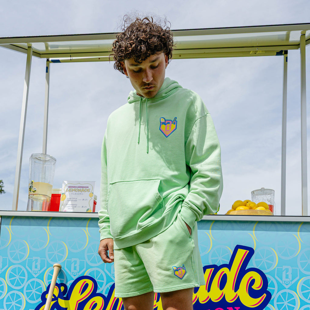 Adult model wearing green hoodie with "Lemonade" design