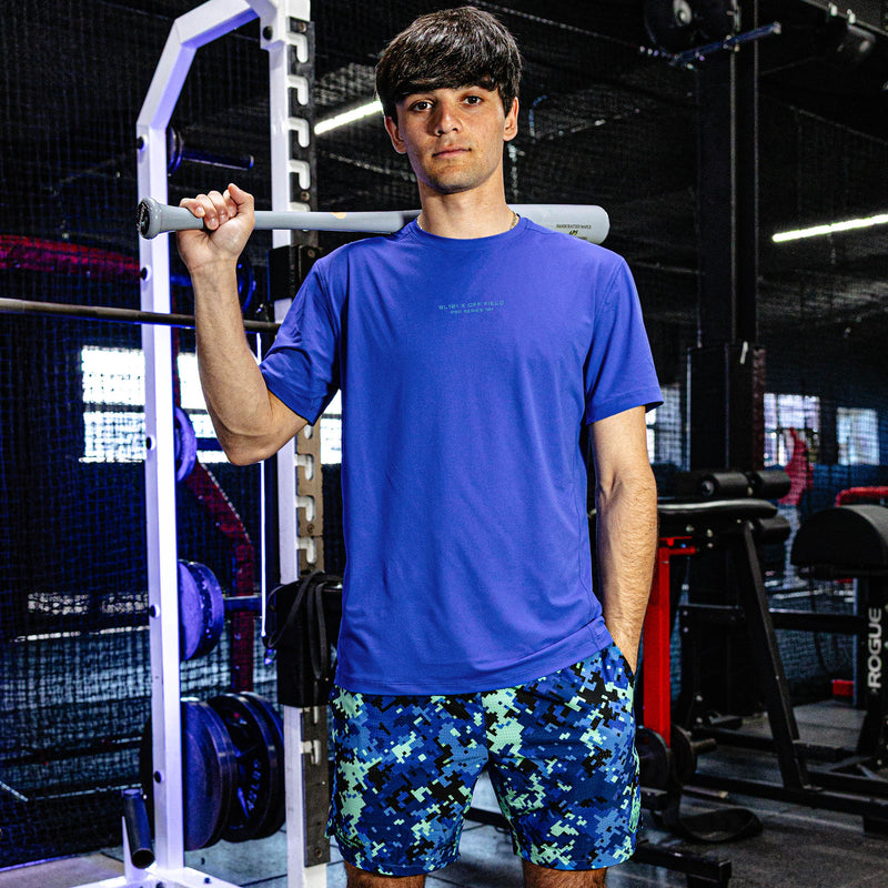 Person wearing a blue t-shirt and patterned shorts in a gym setting