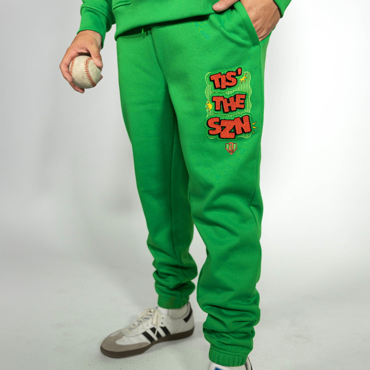Adult model wearing green sweatpants with "Tis The SZN" design