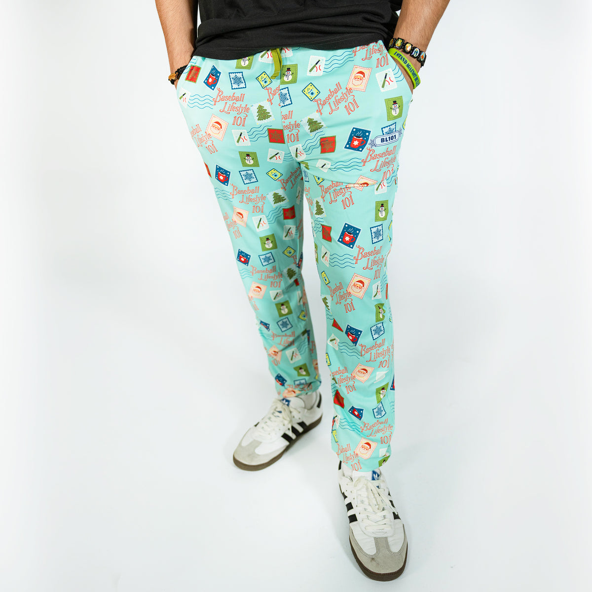 Adult model wearing teal pajama pants with "Holiday Stamps" design