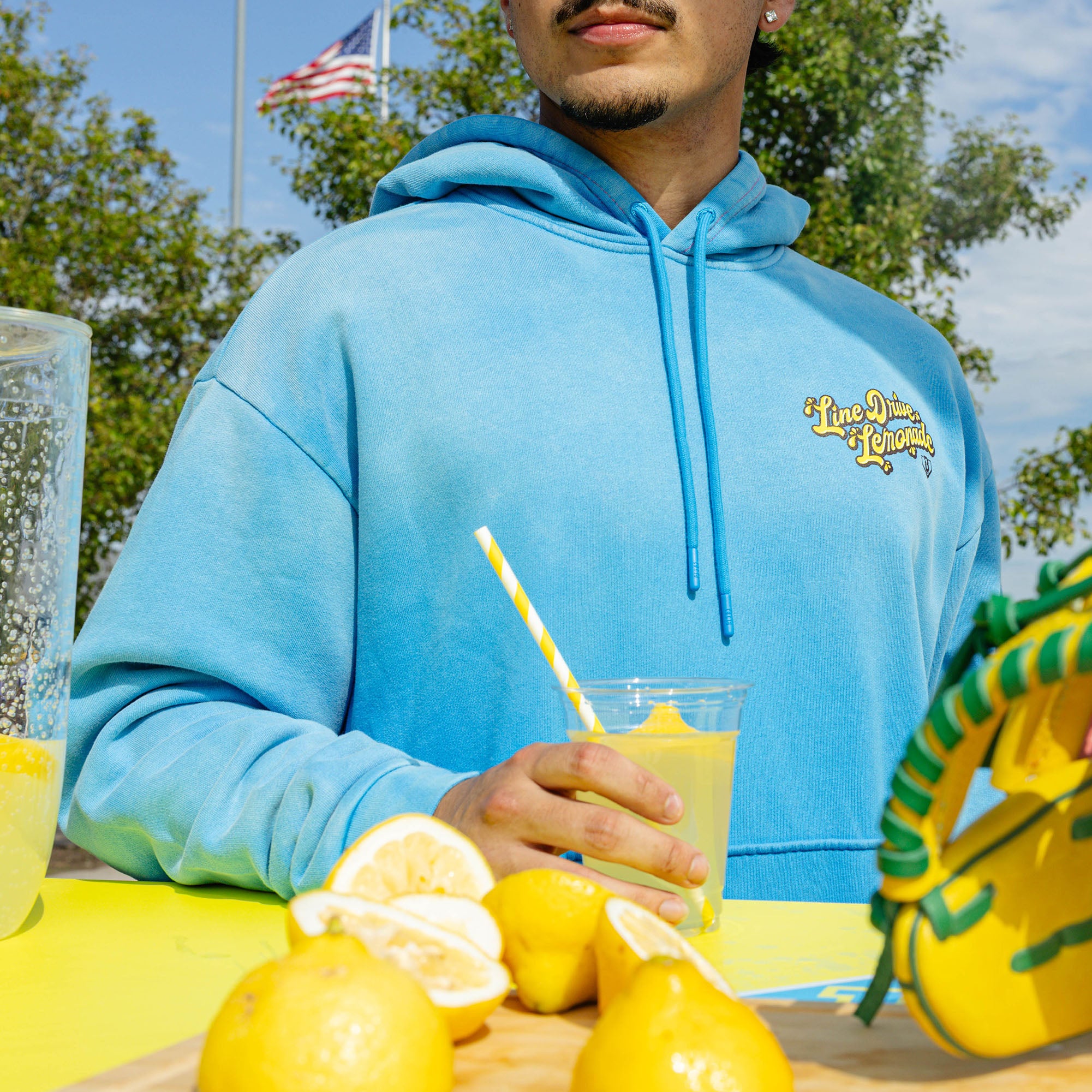 Adult model wearing blue hoodie with "Lemonade Cup" design
