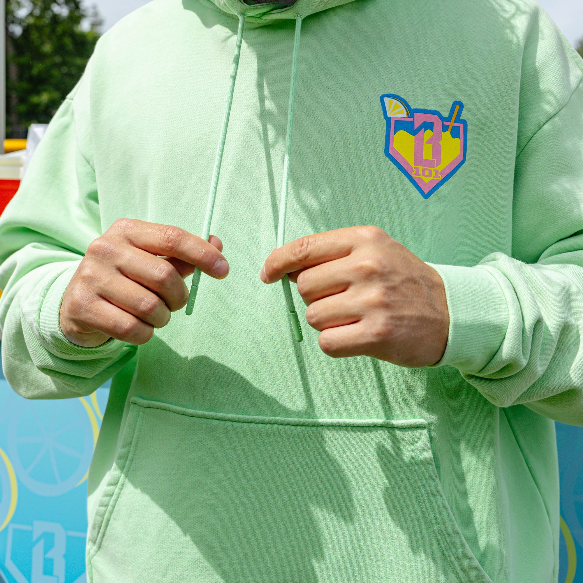 Adult model wearing green hoodie with "Lemonade" design
