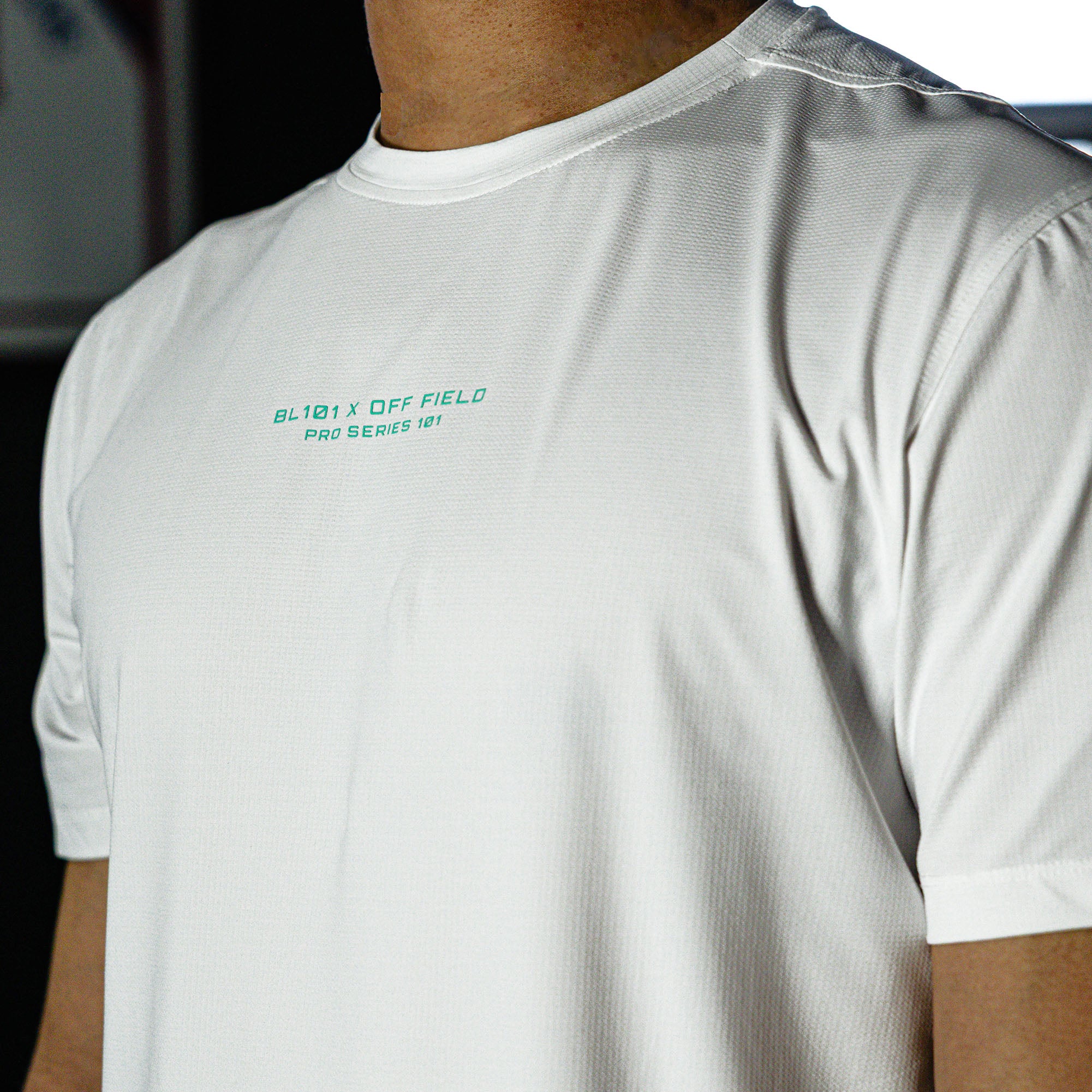 White t-shirt with text on the chest worn by a person, blurred background