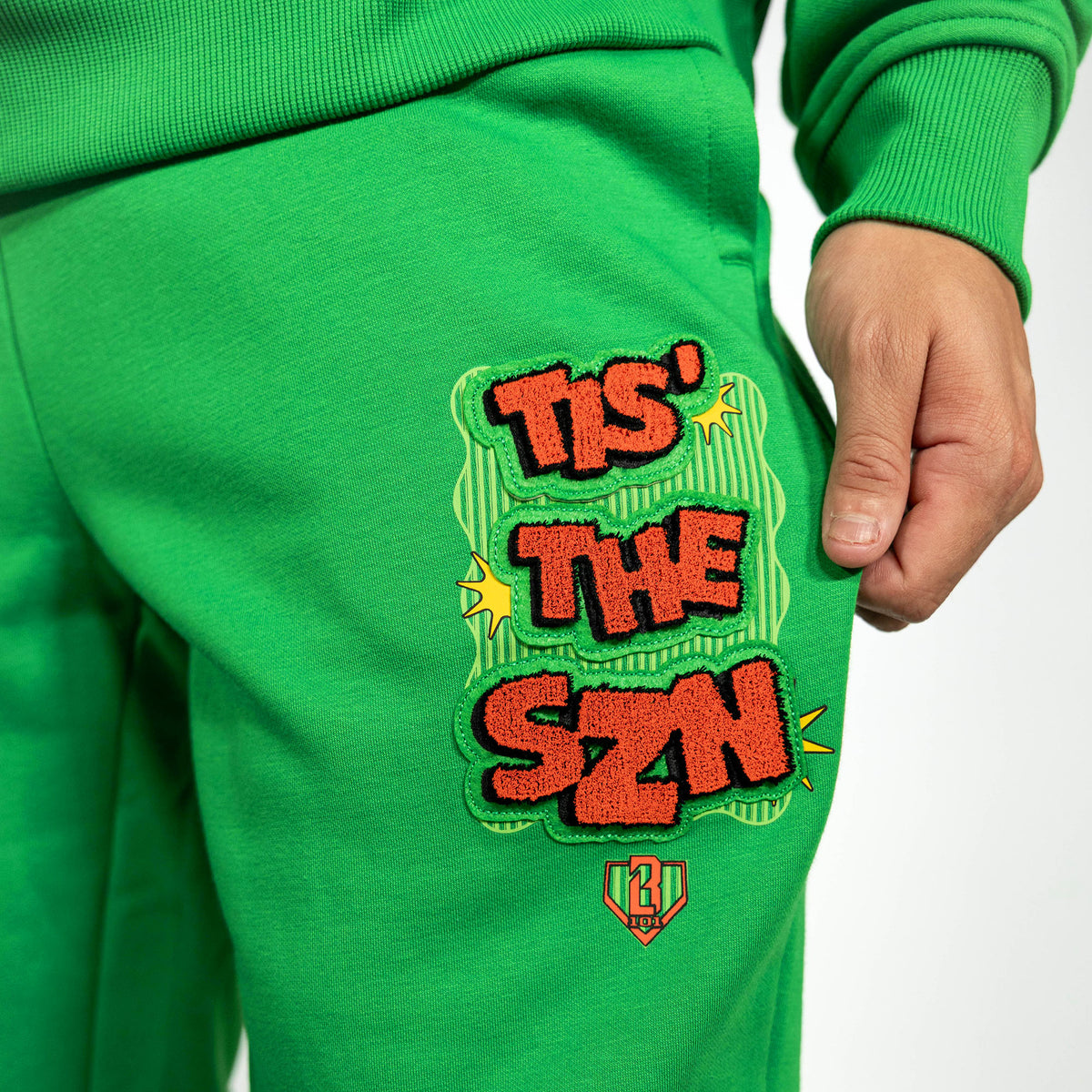 Adult model wearing green sweatpants with "Tis The SZN" design
