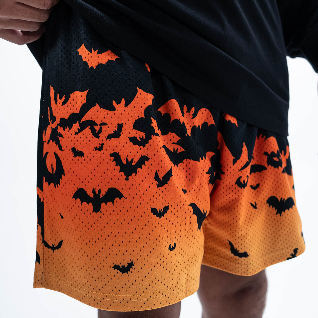 Adult model wearing orange shorts with "Bat Gradient" design