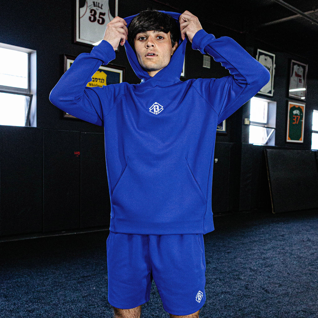 Person wearing a blue tracksuit with a logo in an indoor setting