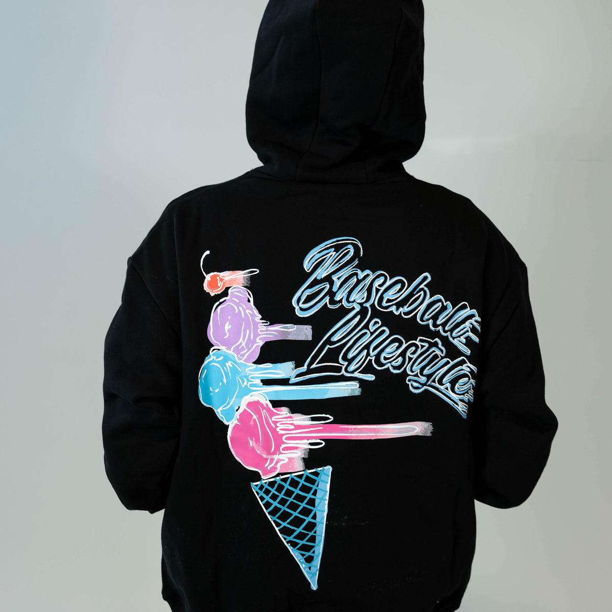 Adult model wearing black hoodie with "Fastball Scoops" design