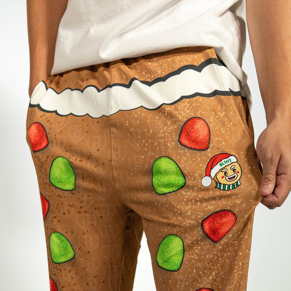 Adult model wearing brown pajama pants with "Gingerbread Rookie" design