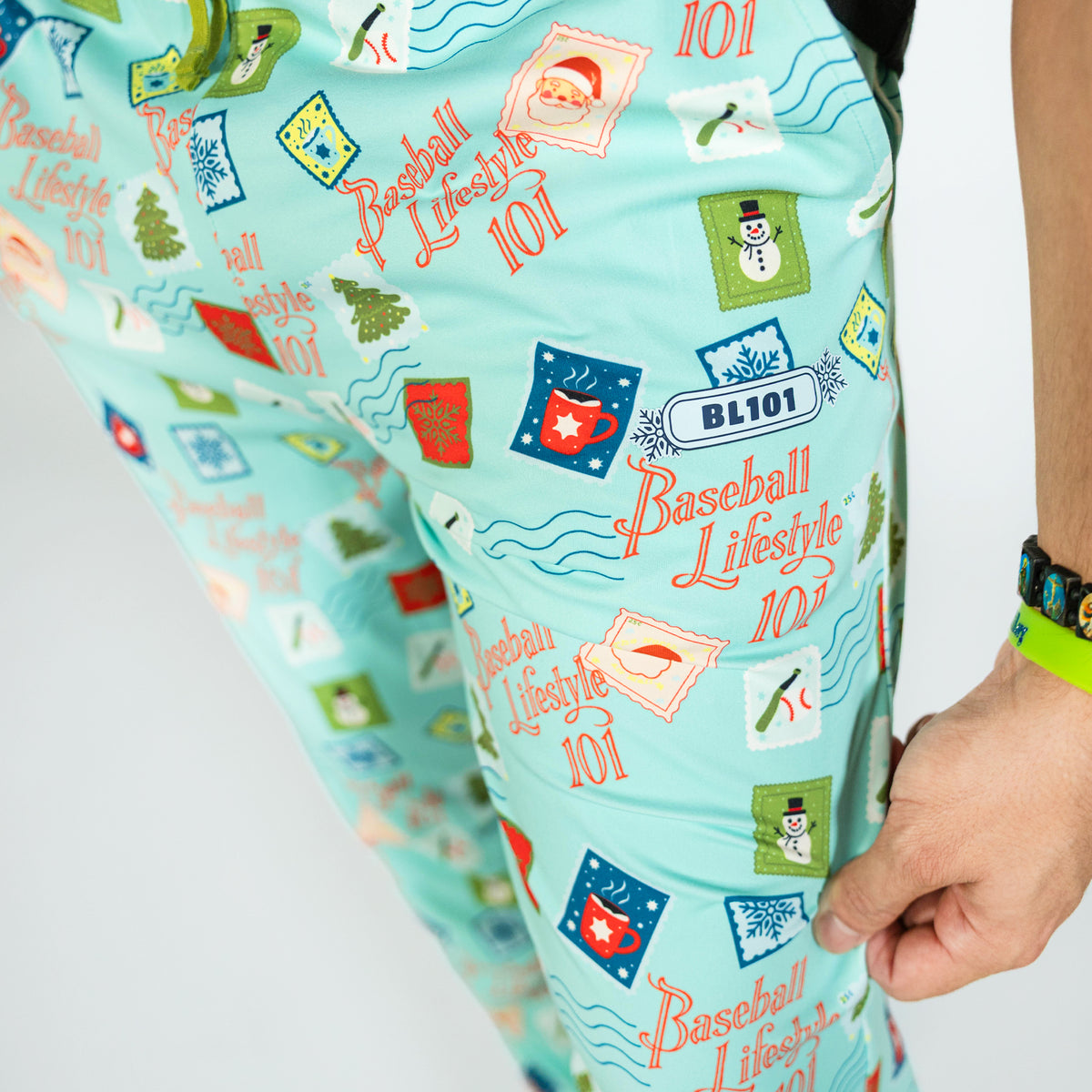 Adult model wearing teal pajama pants with "Holiday Stamps" design