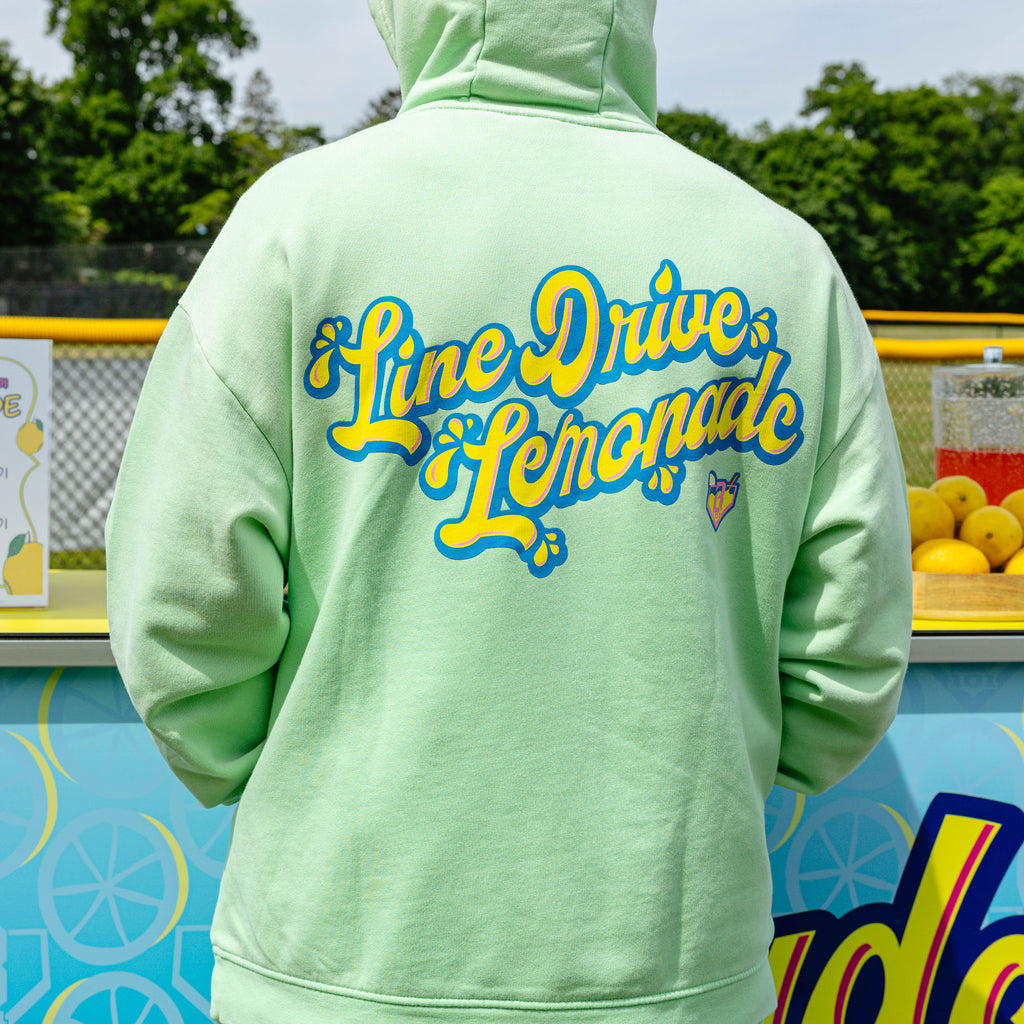 Adult model wearing green hoodie with "Lemonade" design