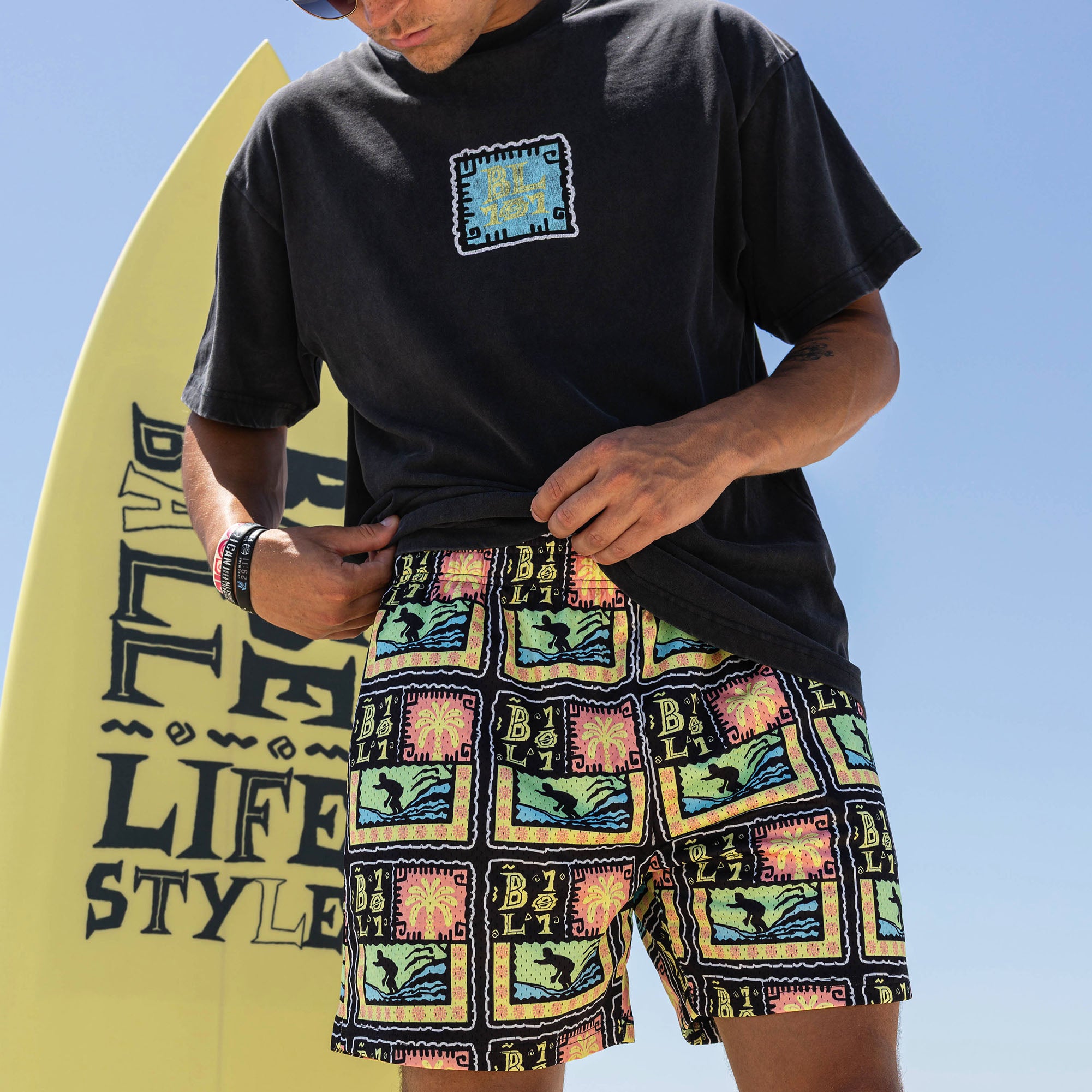 Adult model wearing multi-color shorts with "Wave Goodbye" design