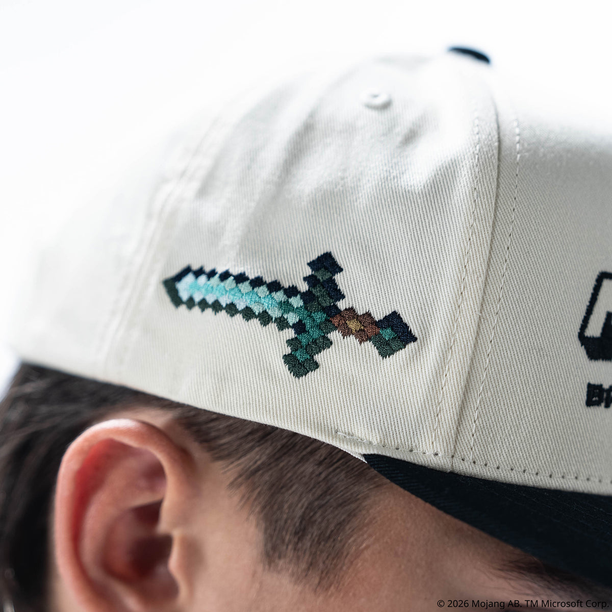 Adult model wearing black and white hat with "BL101 x Minecraft Sword" design