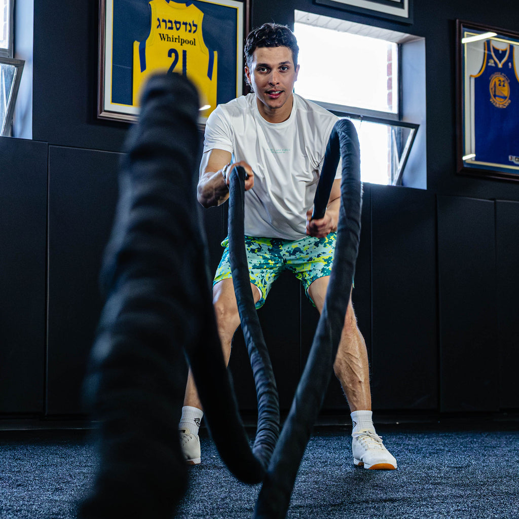 Man using battle ropes in a room with sports jerseys on the wall