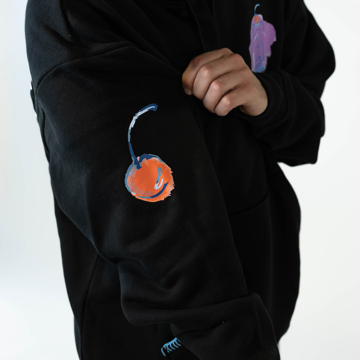 Adult model wearing black hoodie with "Fastball Scoops" design