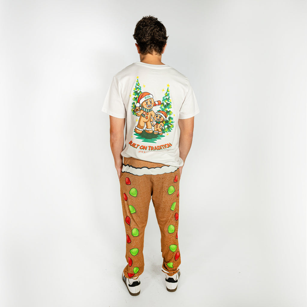 Adult model wearing brown pajama pants with "Gingerbread Rookie" design
