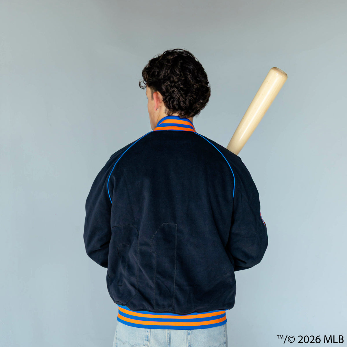 Adult model wearing black New York Mets Stadium bomber jacket