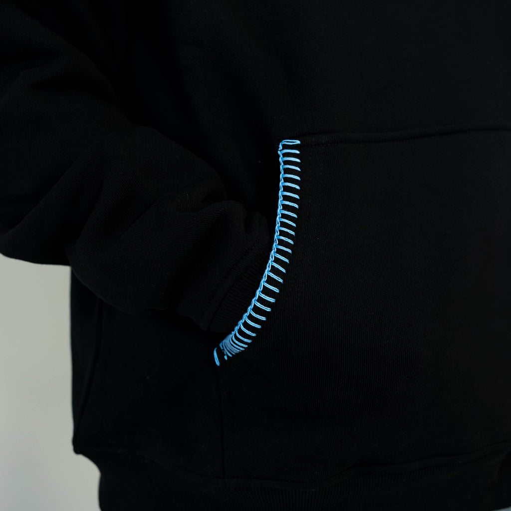 Adult model wearing black hoodie with "Fastball Scoops" design