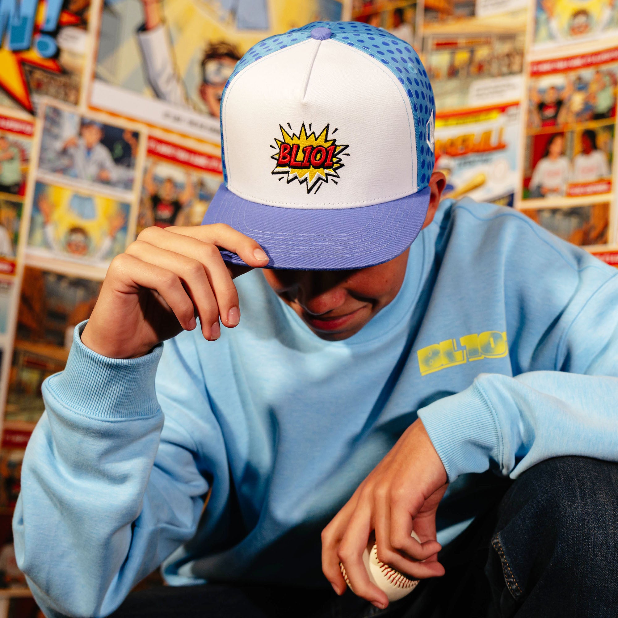 Adult model wearing blue hat with "BL101 Comic" design