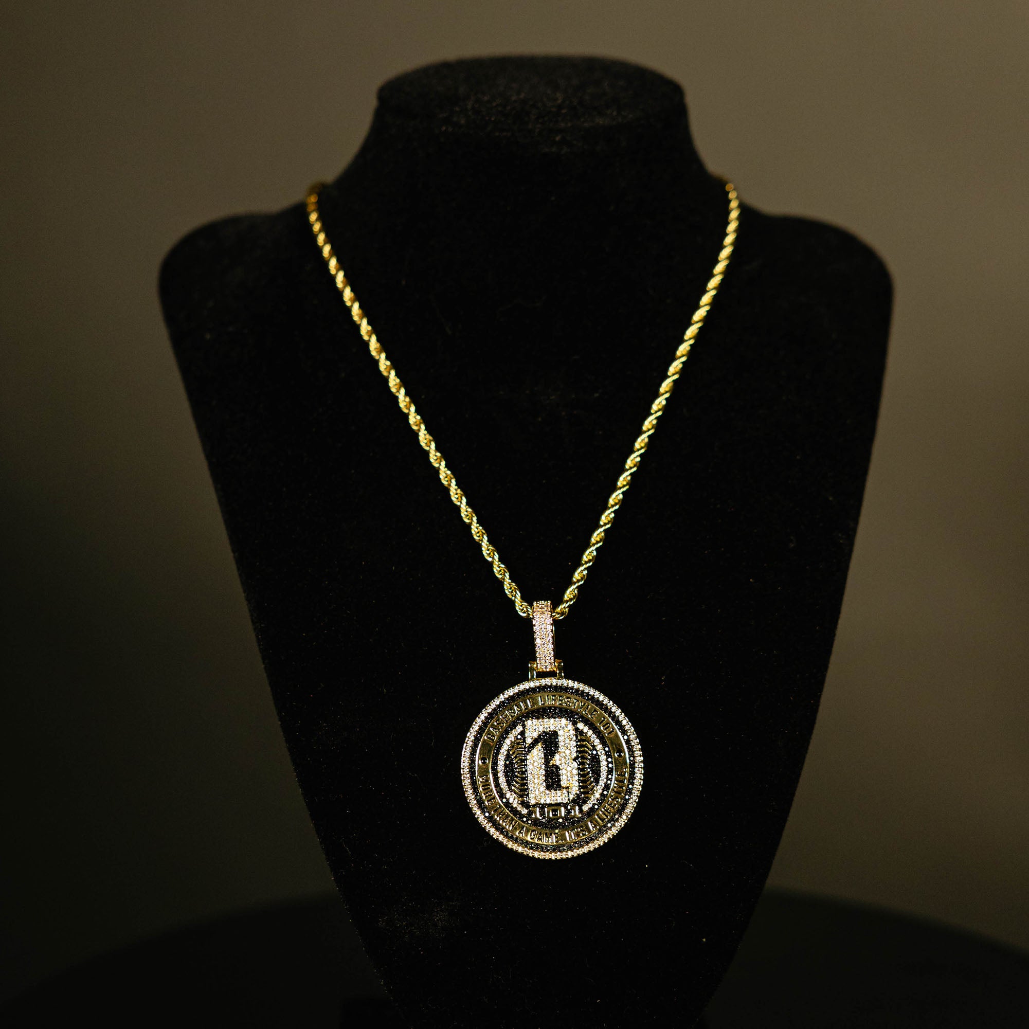 Yellow gold BL101 Medallion necklace hanging on a display stand against a black background