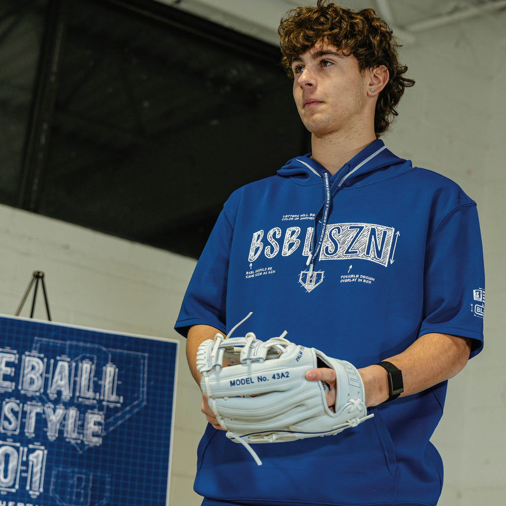 Person wearing a navy shorts sleeve blue hoodie with white blueprint 'BSBL SZN' text and white 'bsbl v3' logo