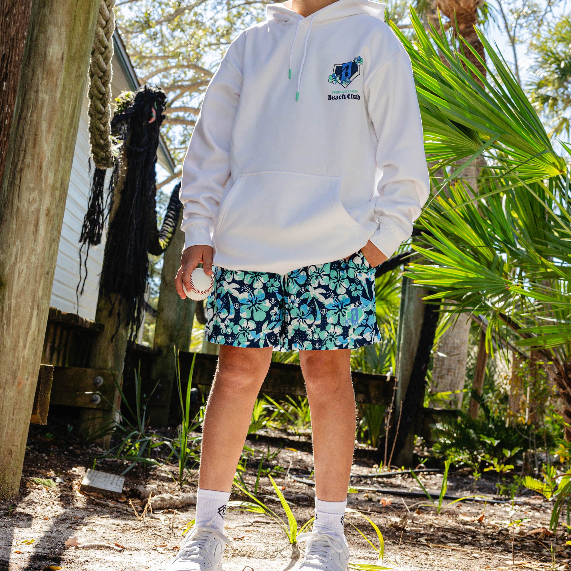 Person wearing a white hoodies with floral B101 logo and 'Swing into Spring Beach Club'