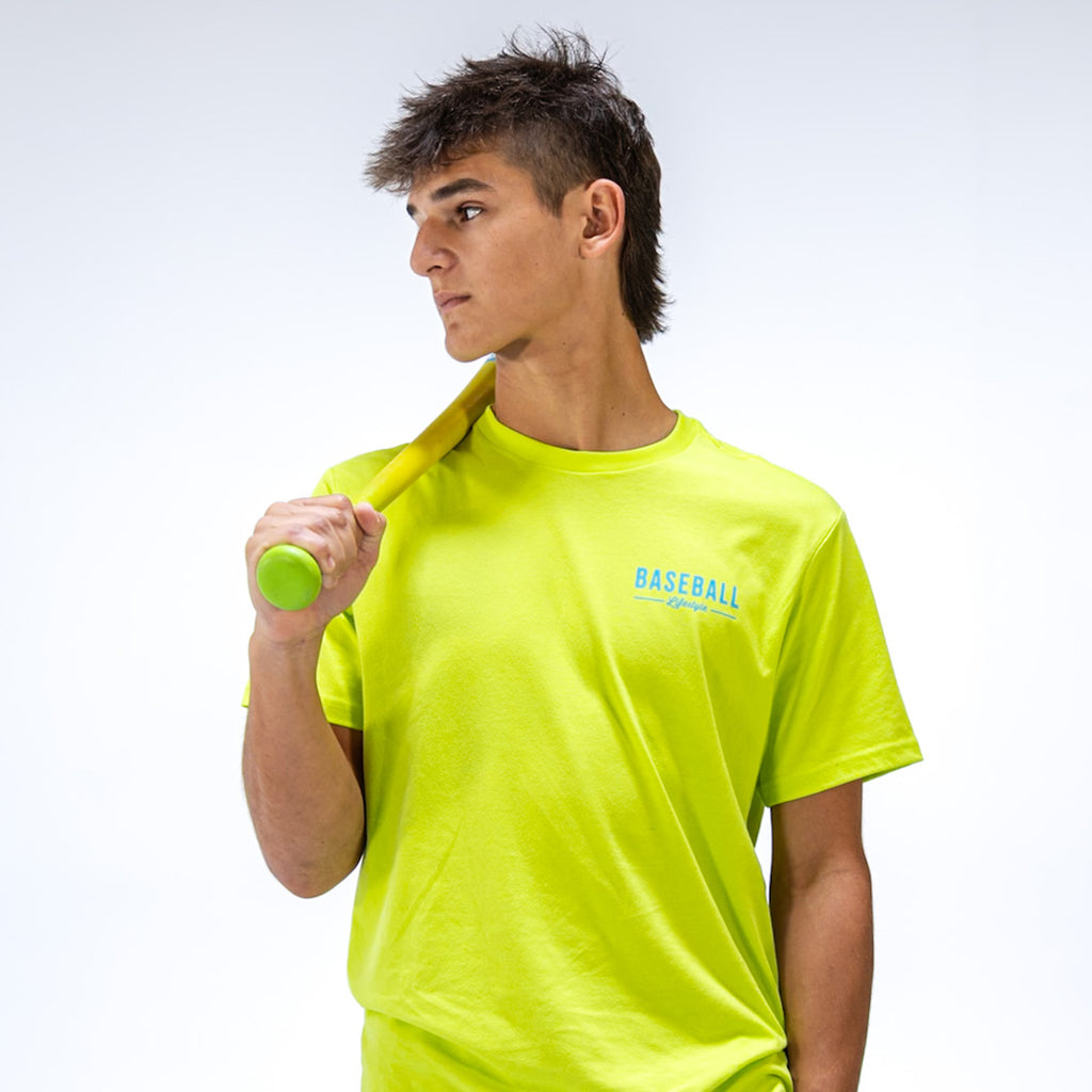 Person wearing a bright yellow t-shirt with 'BASEBALL Lifestyle 101' text, holding a green bat against a white background