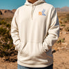 Person wearing a beige hoodie with a logo in a desert setting