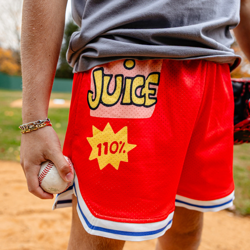 Person wearing red shorts with 'Juice' and '110%' text on a baseball field