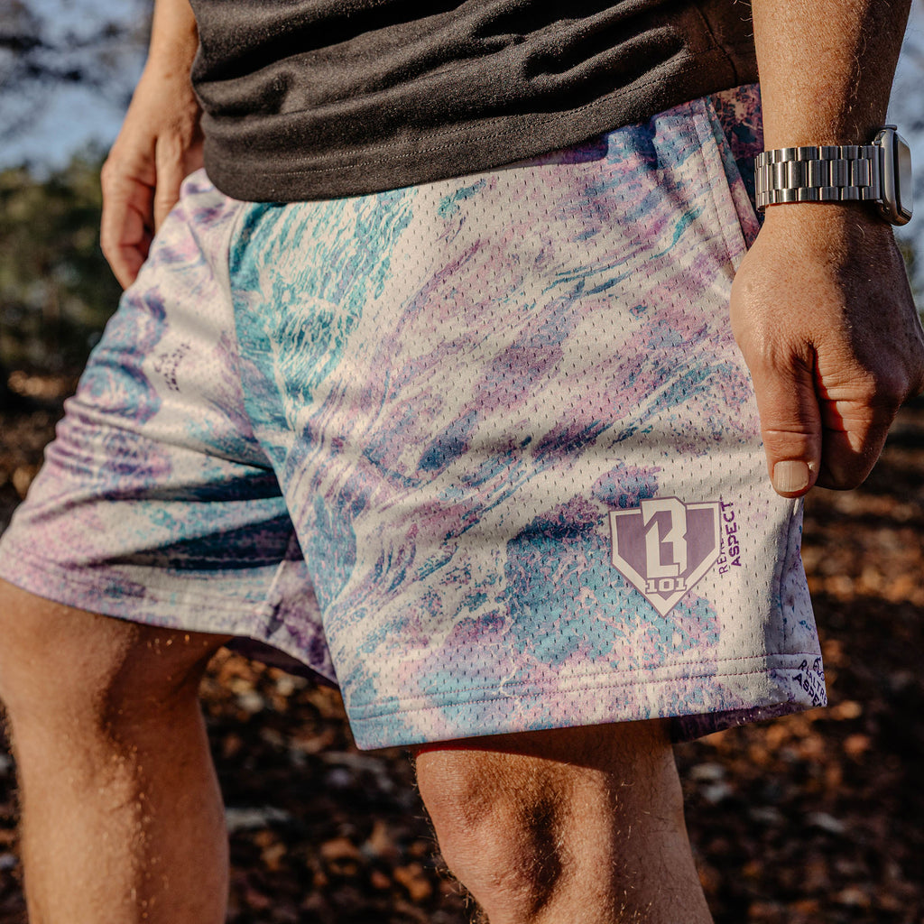 Man wearing marbled purple, white and blue shorts, outside.