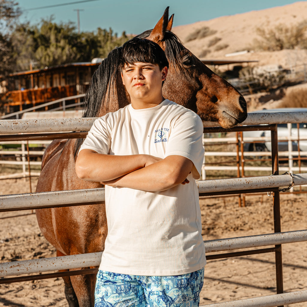 Adult model wearing white graphic tee with “Saddle Up N Swing Relaxed” design